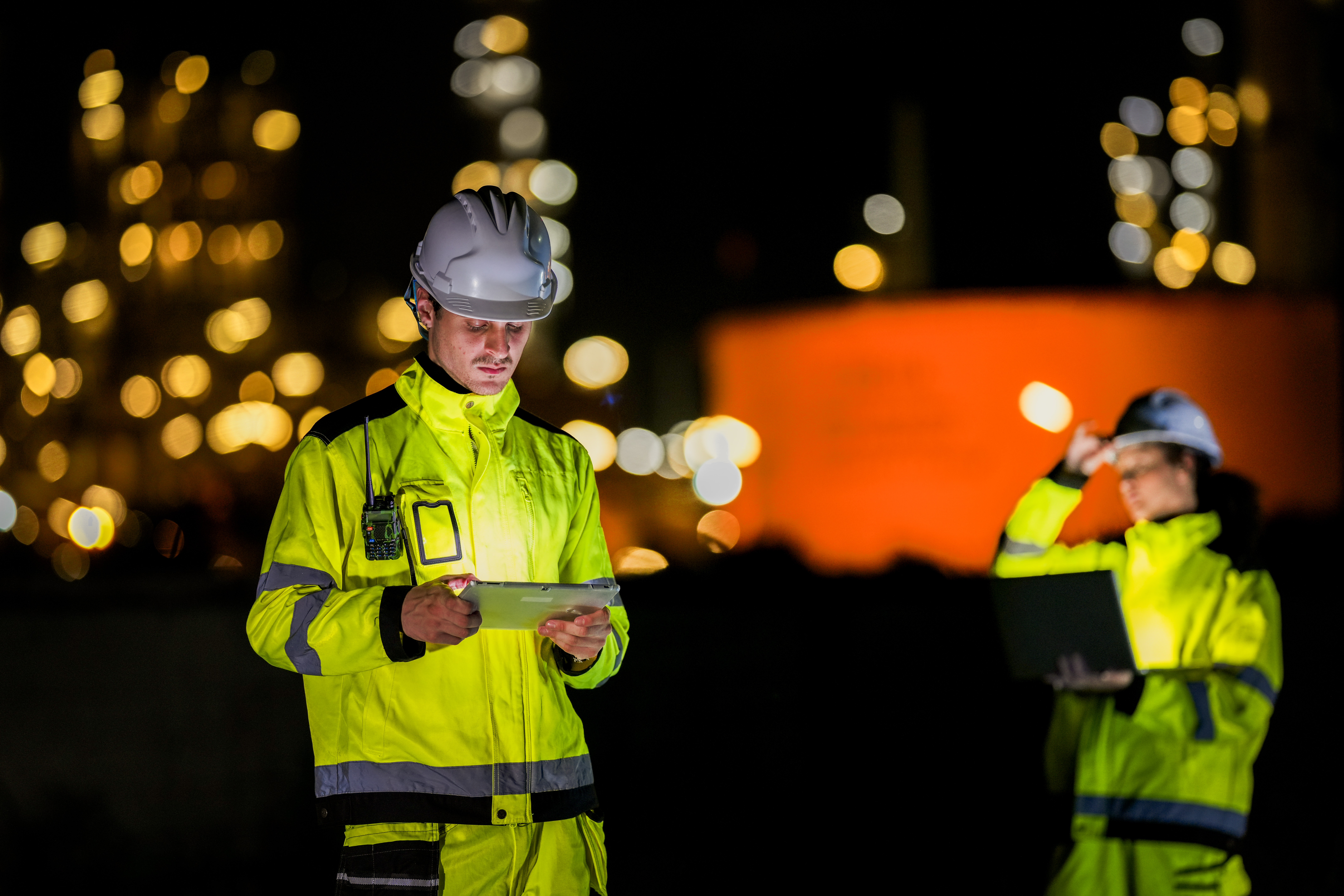 Construction engineers reviewing a tablet at night